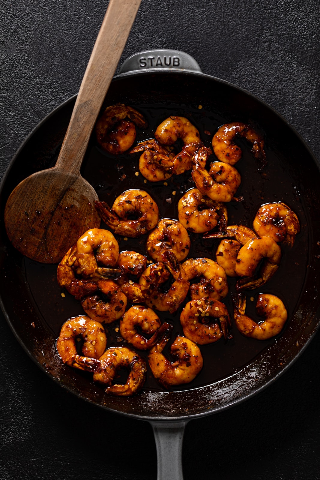 Wooden spoon stirring a skillet of Gochujang Shrimp