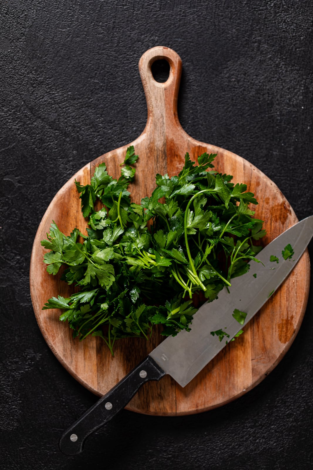 Cilantro and a knife on a wooden cutting board