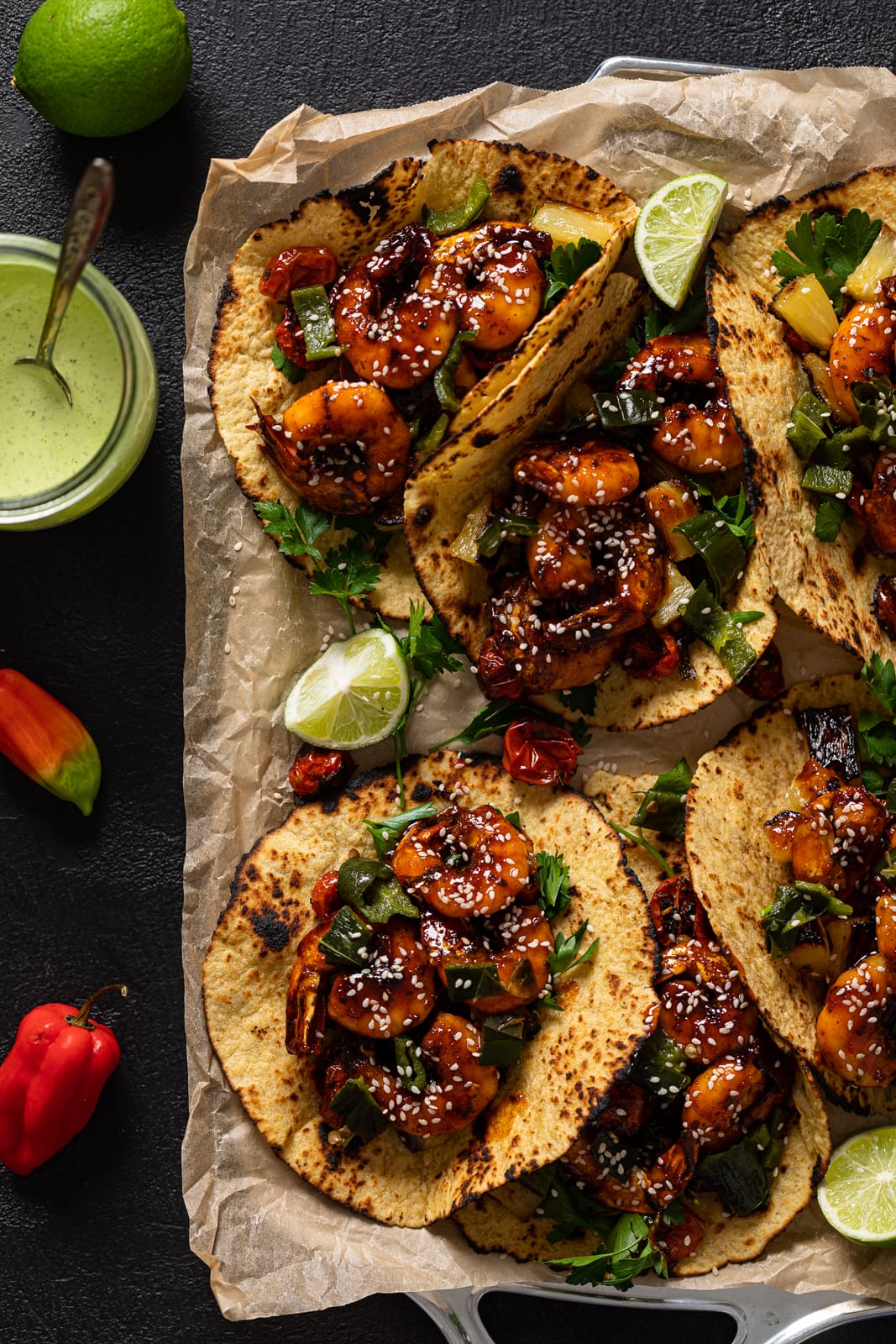 Overhead shot of several Gochujang Shrimp Tacos next to a jar of cilantro lime sauce