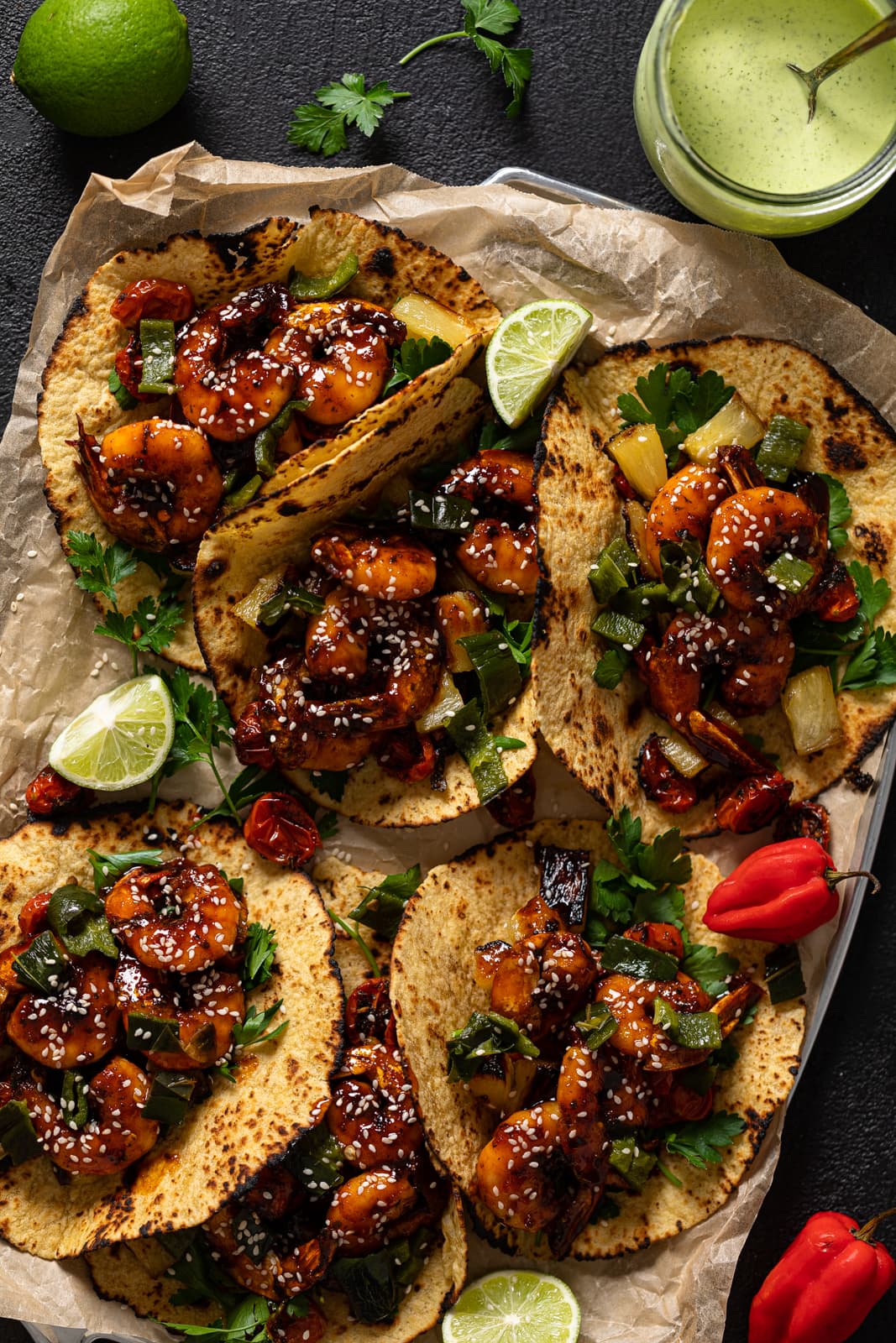 Gochujang Shrimp Tacos with lime wedges and peppers