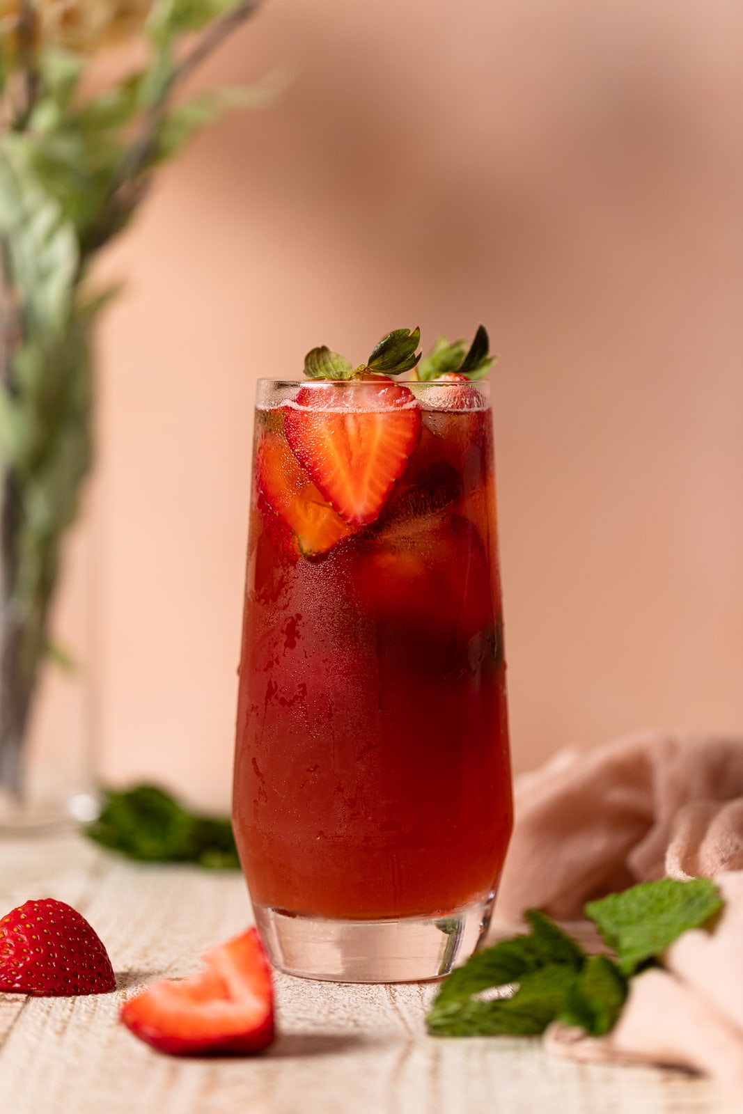 Glass of red Southern Strawberry Iced Sweet Tea topped with strawberry halves