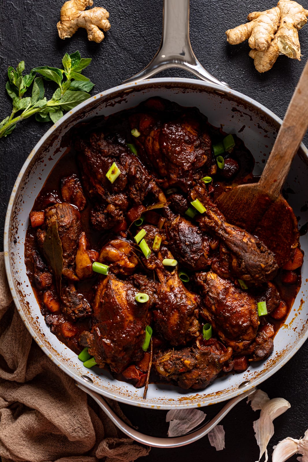 Wooden spoon in a pan of Jamaican Brown Stew Chicken