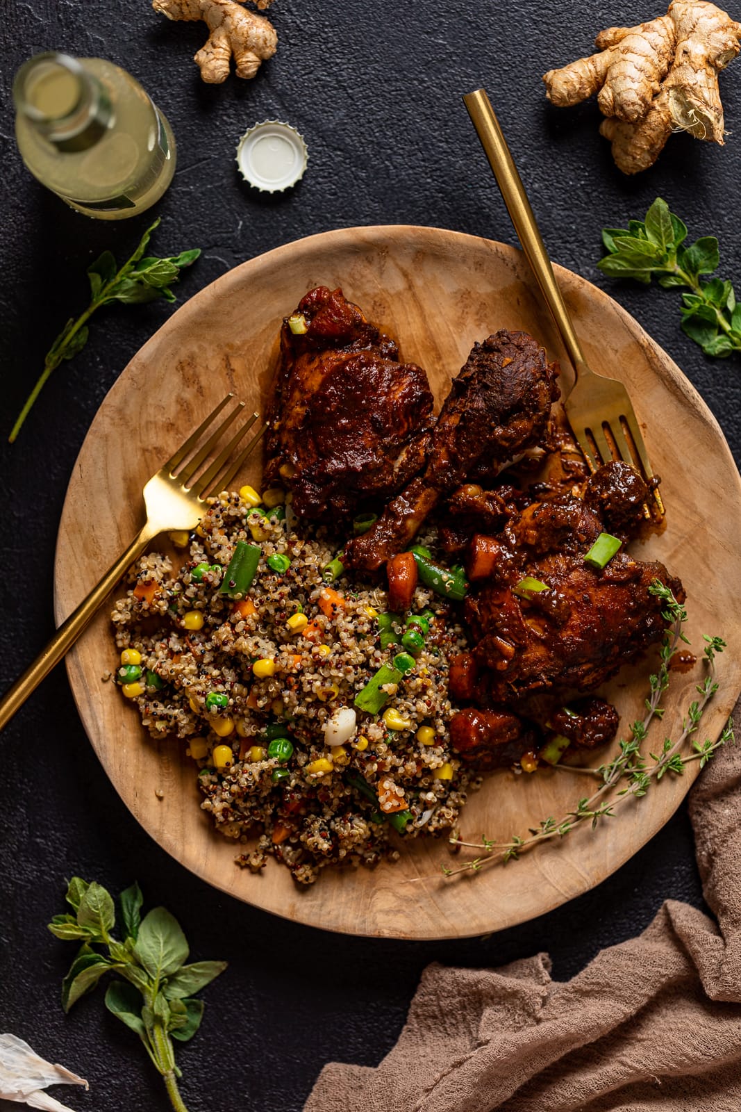 Wooden plate of Jamaican Brown Stew Chicken with a side of grains and vegetables