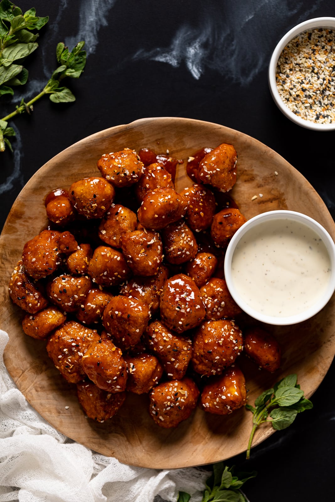 Overhead shot of a plate of Everything Bagel Cauliflower Bites with a bowl of white dip