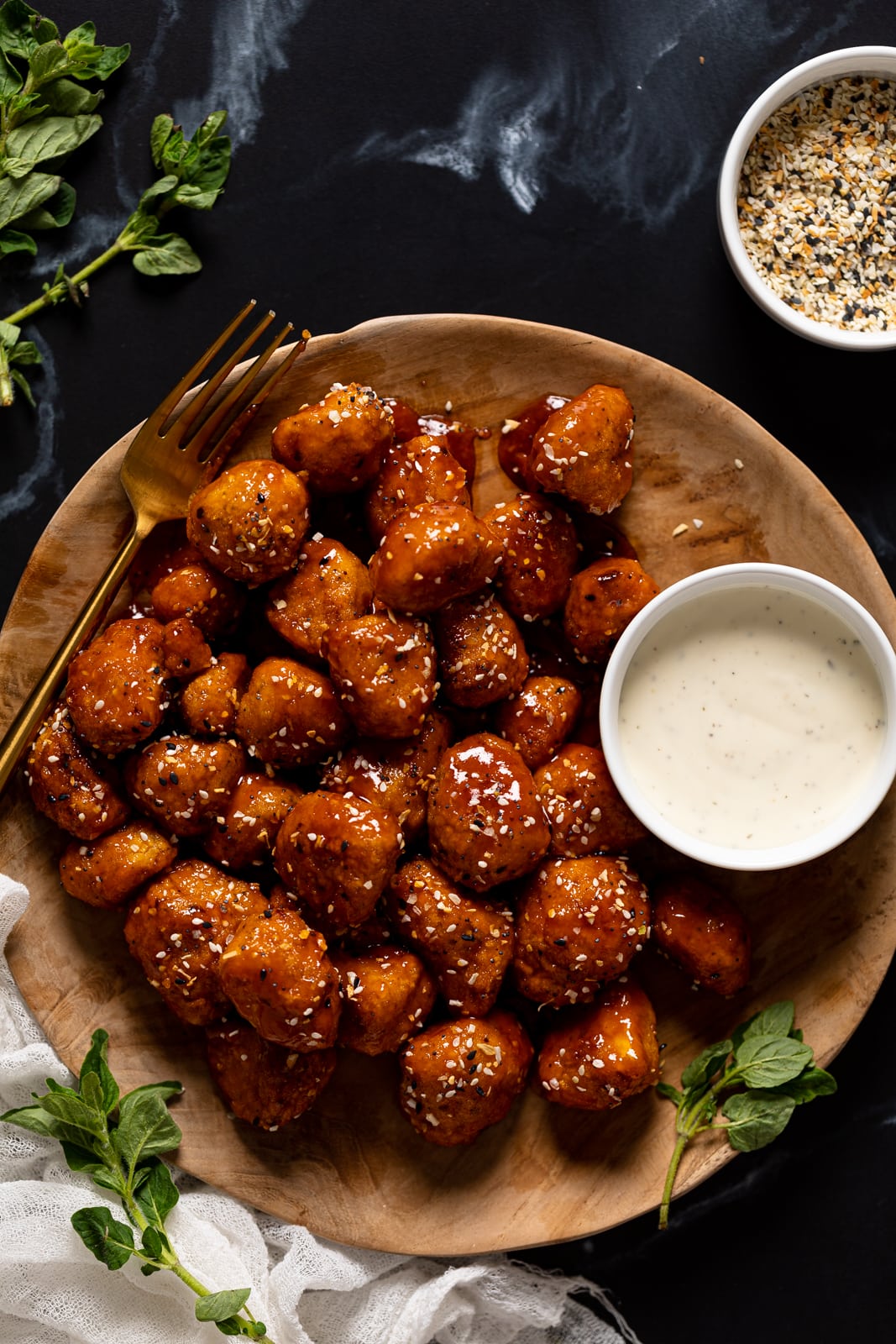 Overhead shot of a plate of Everything Bagel Cauliflower Bites with a bowl of white dip