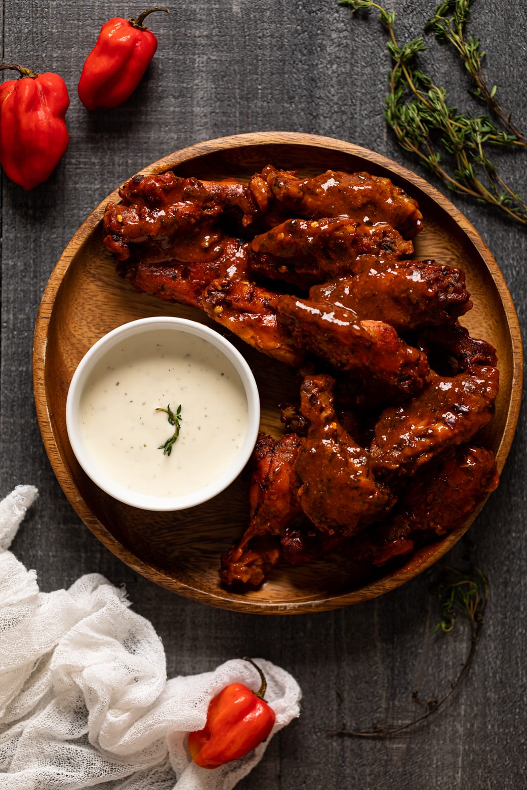 Overhead shot of Oven Baked Buffalo Wings on a wooden plate with a small bowl of dip