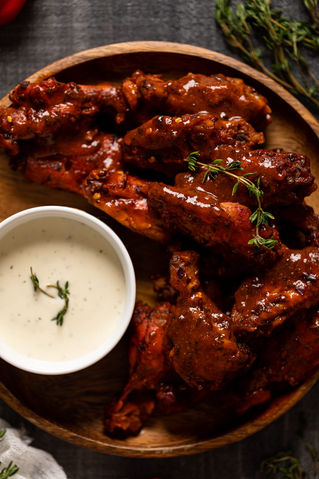 Closeup of Oven Baked Buffalo Wings on a wooden plate with a small bowl of dip
