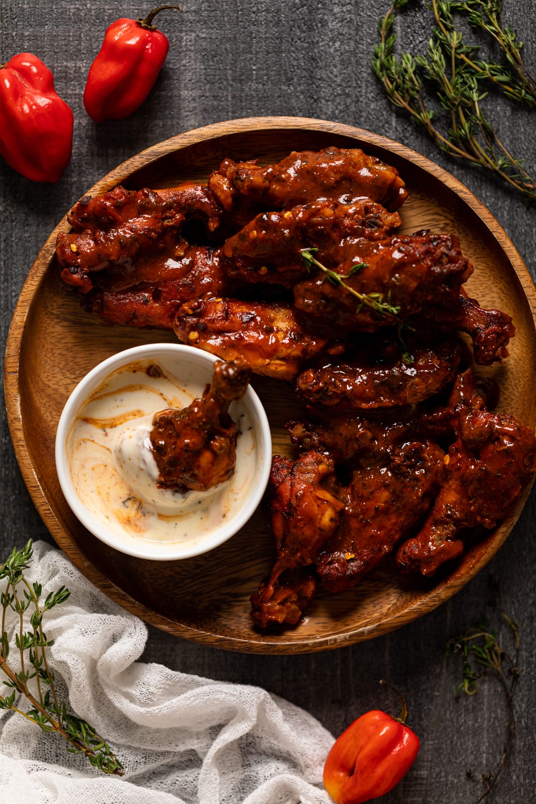 Oven Baked Buffalo Wings on a wooden plate with a small bowl of dip that has a wing in it