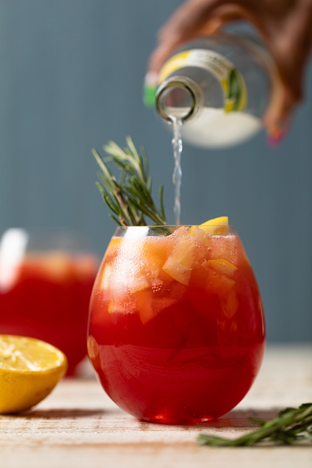 Lemon soda pouring from a bottle into a Cranberry Lemon Spritzer with Lemonade Ice Cubes