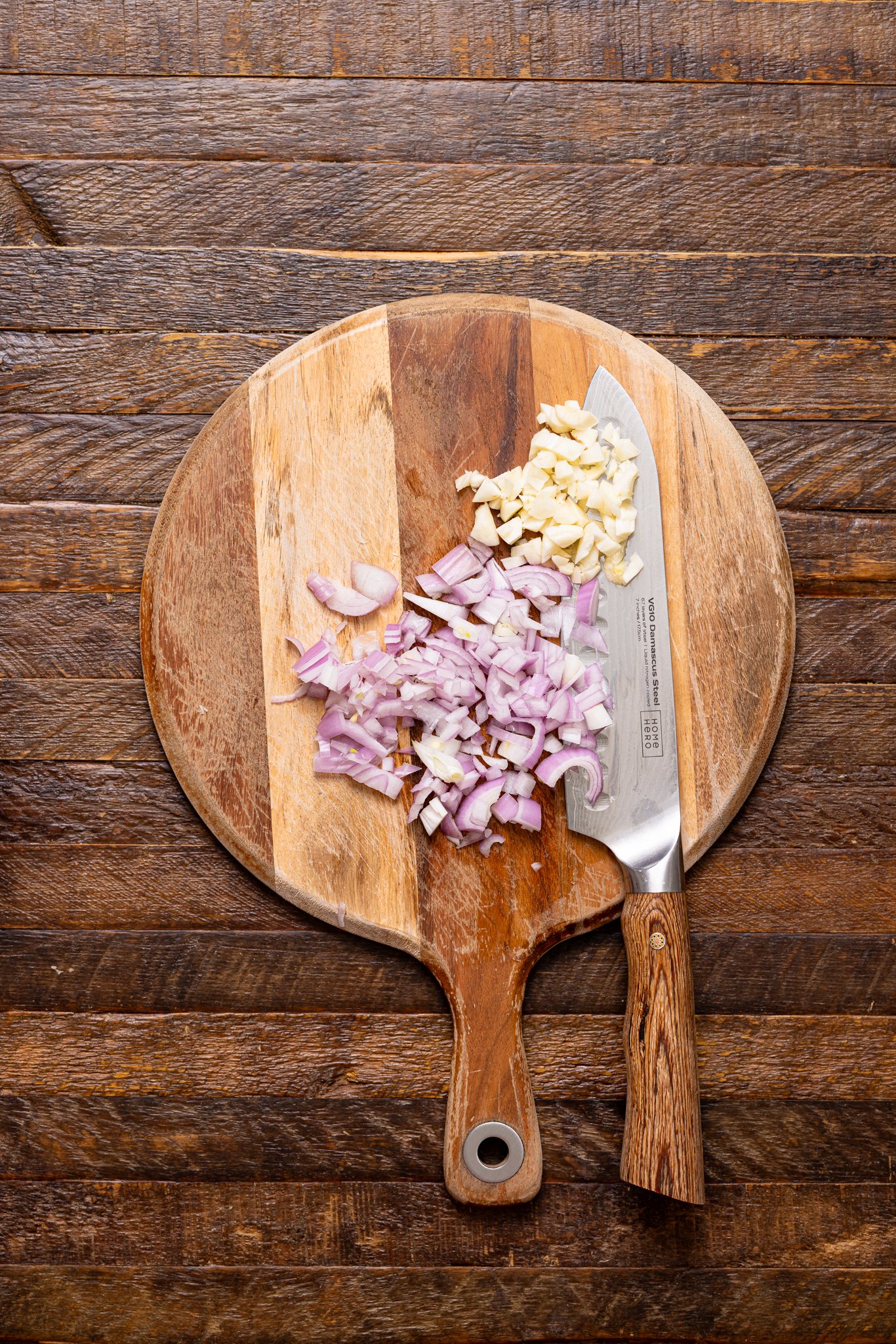 Chopped onions on a cutting board with a knife.