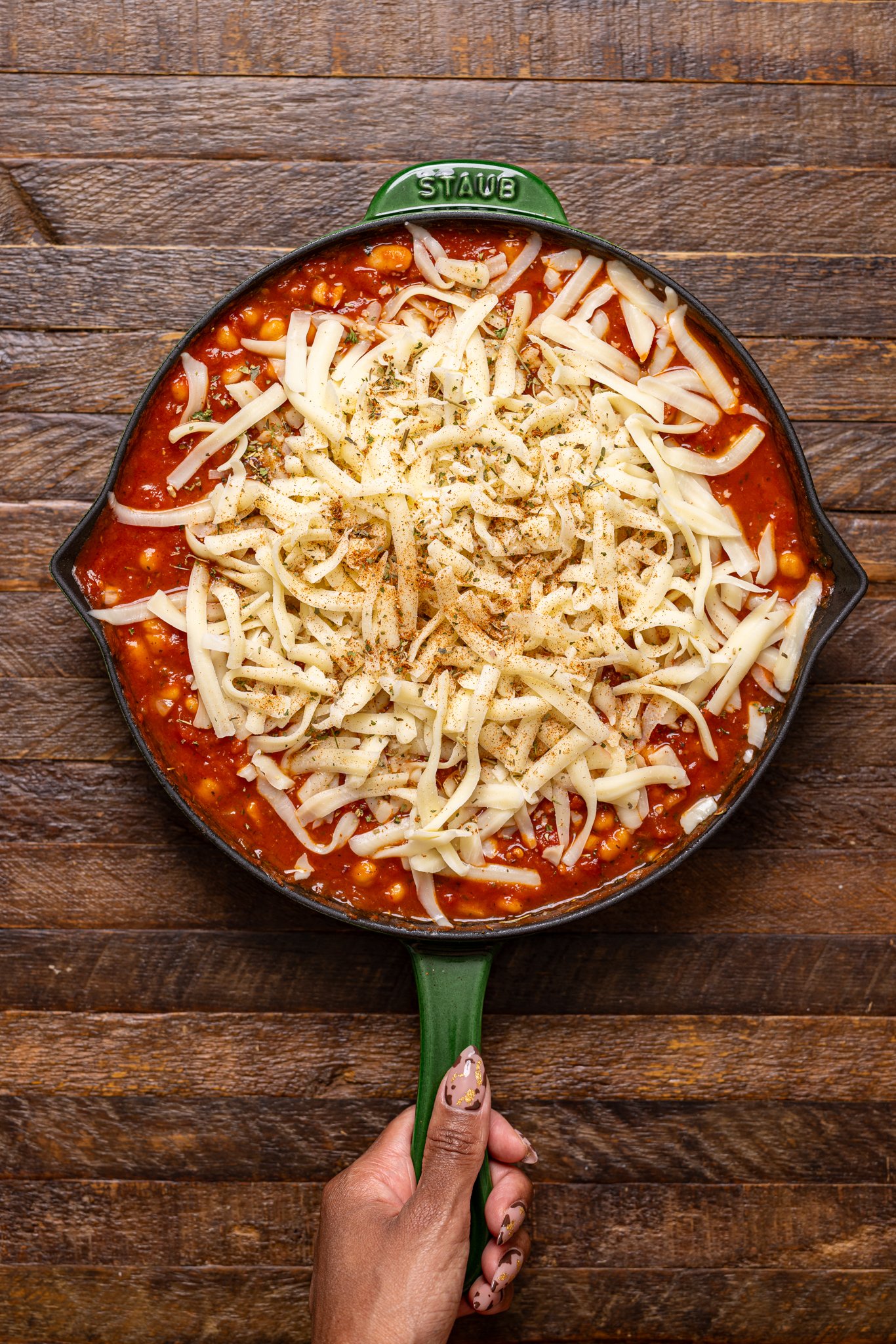All ingredients together in a skillet being held by woman hands.