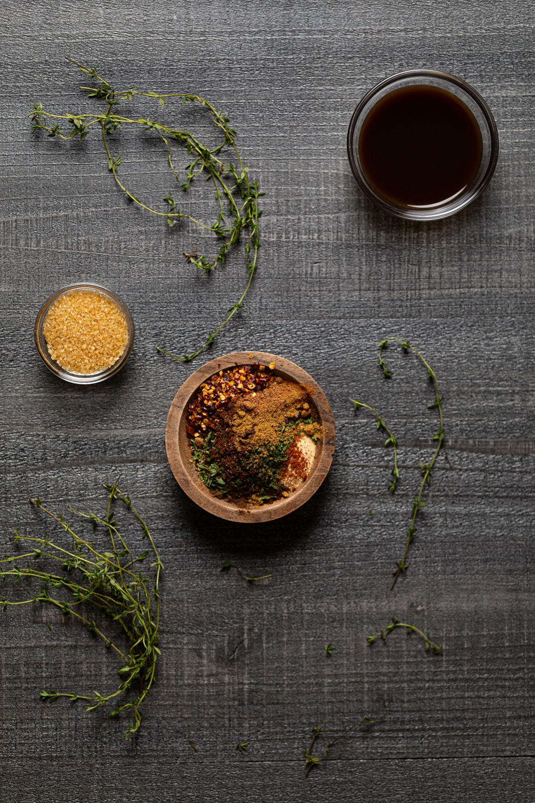 Bowl of jerk seasoning near thyme leaves and other flavorings