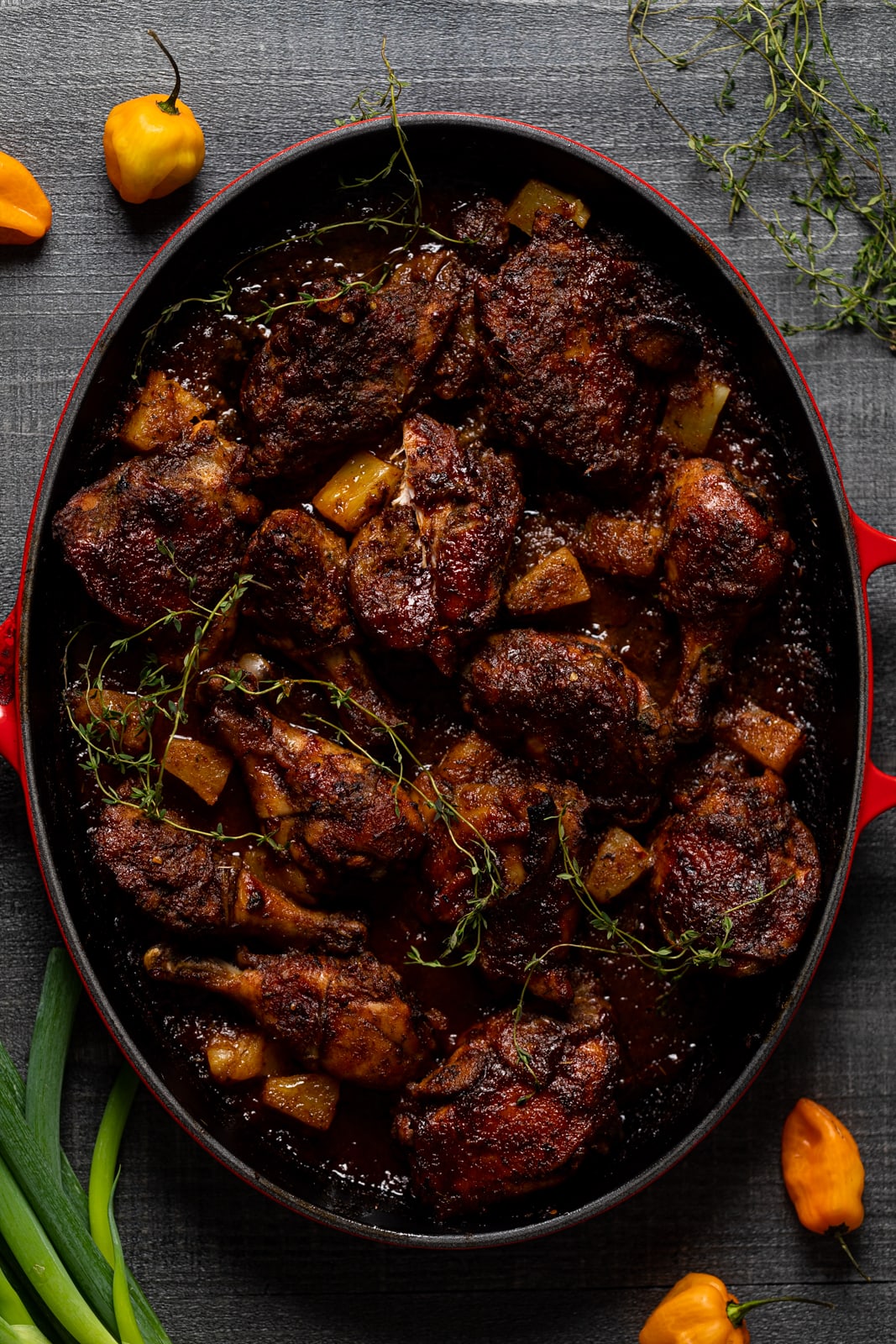 Overhead shot of a red Dutch oven of Baked Jamaican Pineapple Jerk Chicken