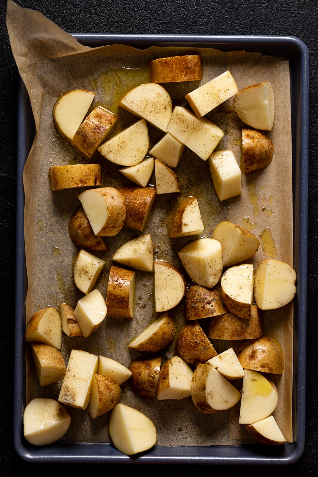 Seasoned, diced potatoes on a baking sheet