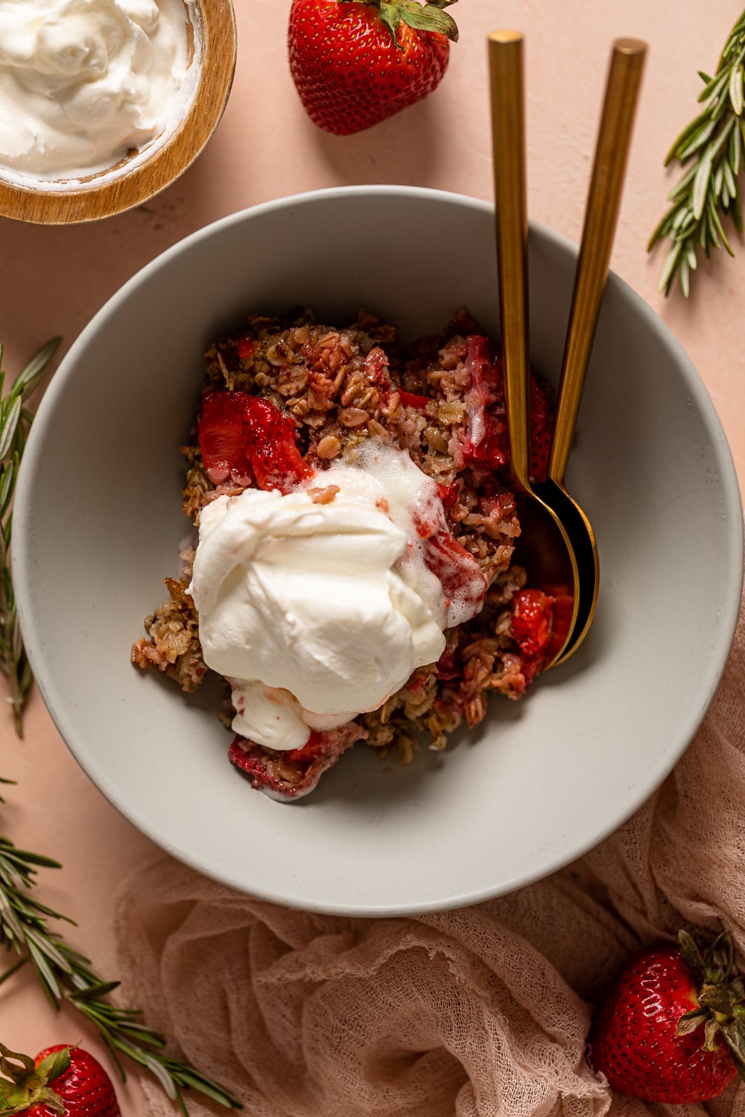 Bowl of Strawberry Shortcake Baked Oats topped with strawberry sauce and coconut whipped cream