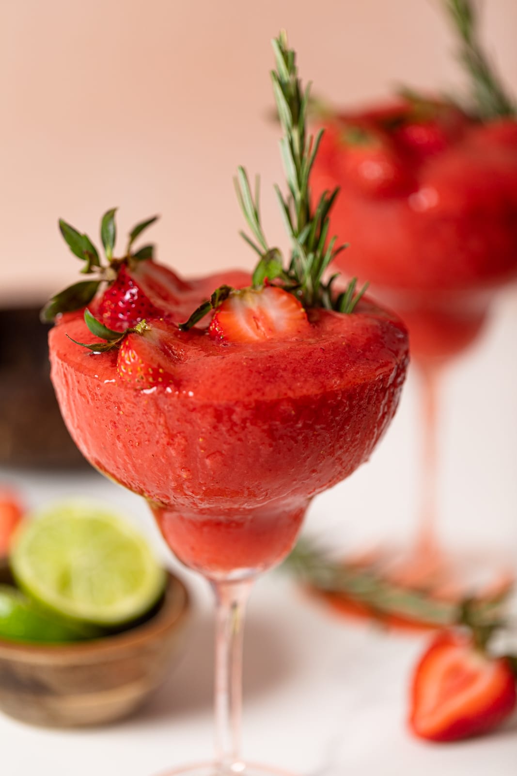 Frozen Cucumber Watermelon Strawberry Mocktail topped with halved strawberries and a sprig of rosemary