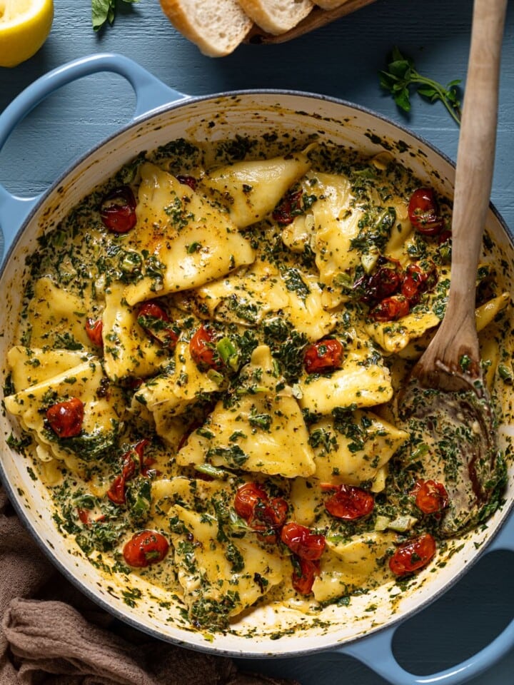 Overhead shot of a wooden spoon scooping Creamy Tuscan Ravioli