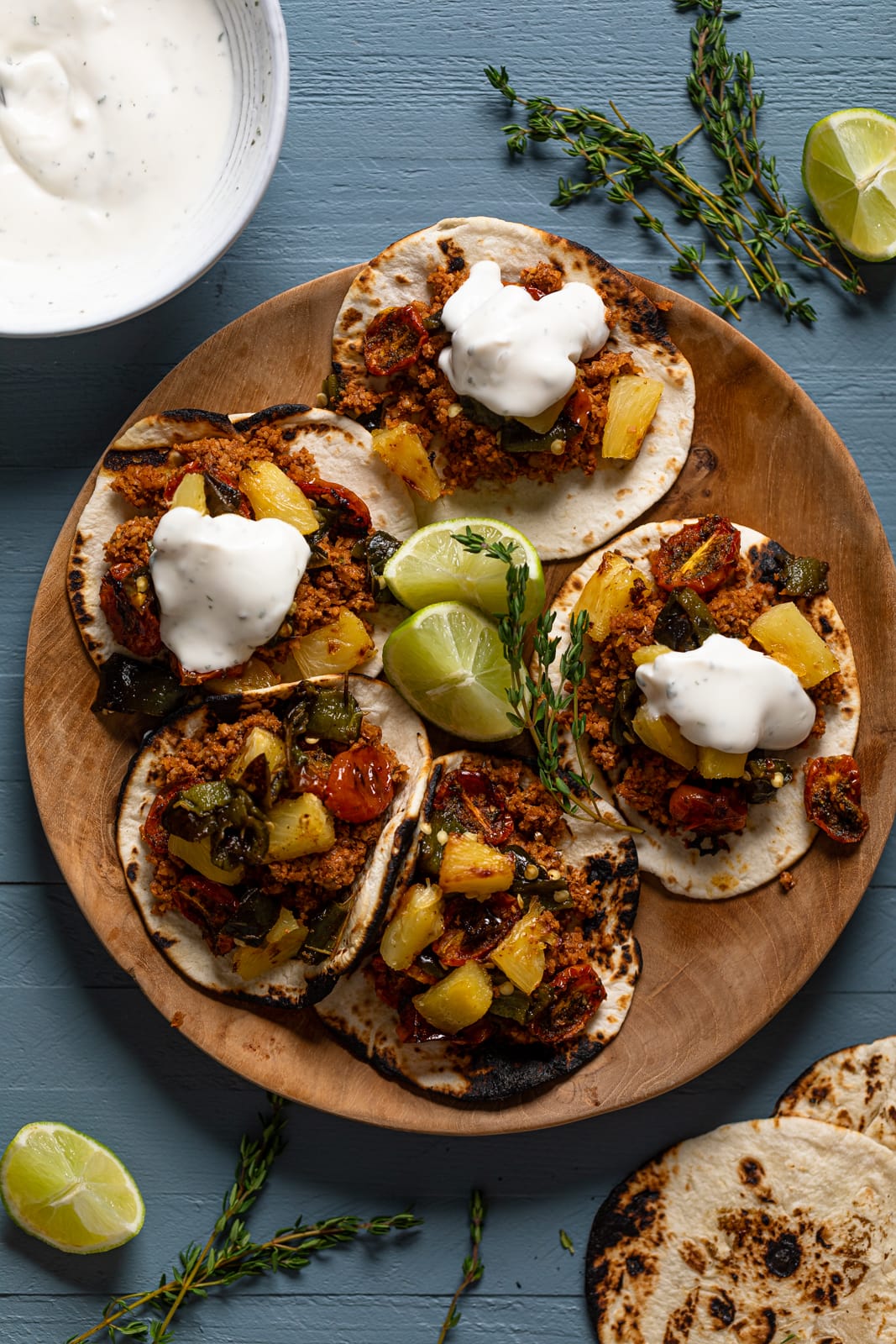 Wooden plate of Vegan Jamaican Jerk Walnut Tacos surrounding lime wedges