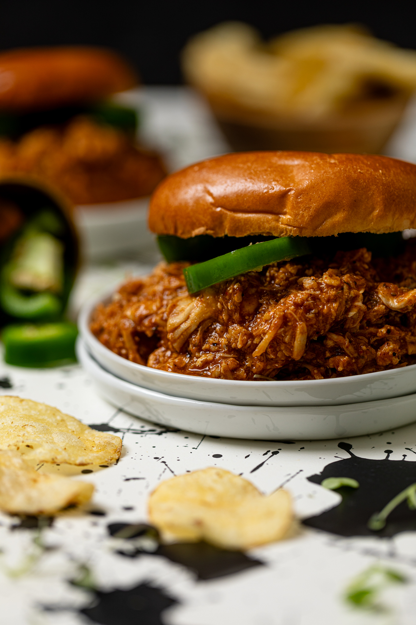 Best BBQ Pulled Chicken Sandwich with a side of chips and sliced jalapenos.