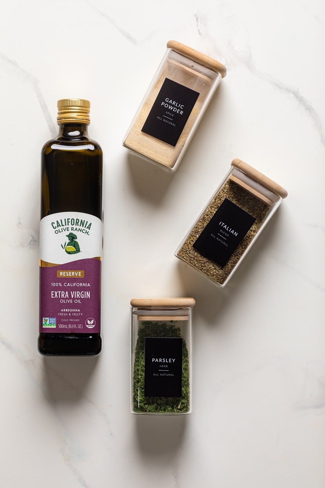 Jars of olive oil, garlic powder, parsley, and Italian seasoning