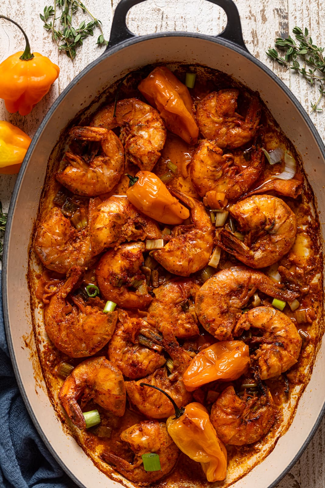 Jamaican Spicy 'Pepper' Shrimp in a Dutch oven next to scotch bonnet peppers