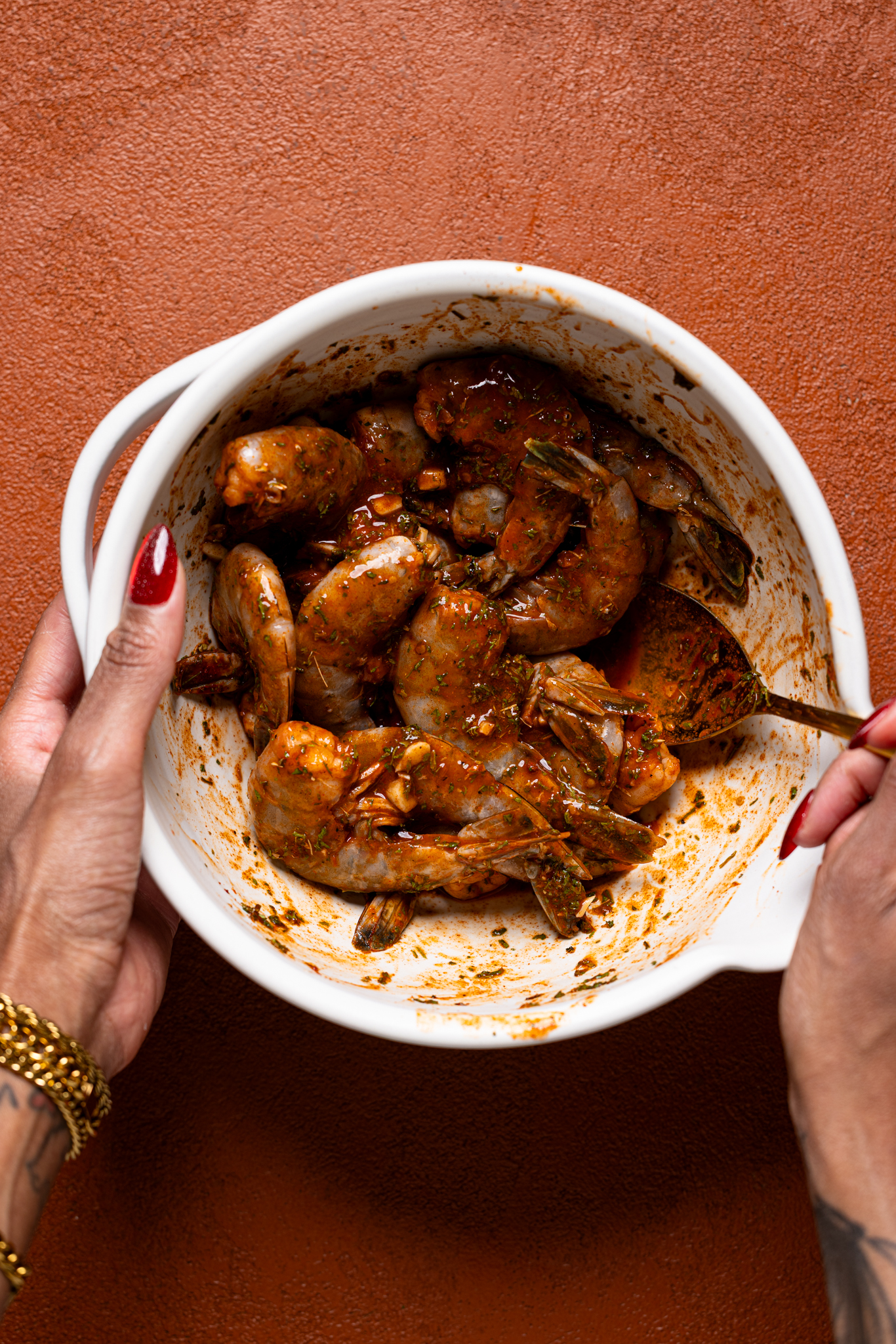 Marinated shrimp being stirred in a bowl with woman hands.