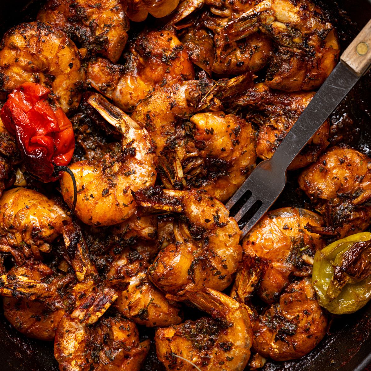 Up close shot of Jamaican Pepper Shrimp in a skillet with a fork.