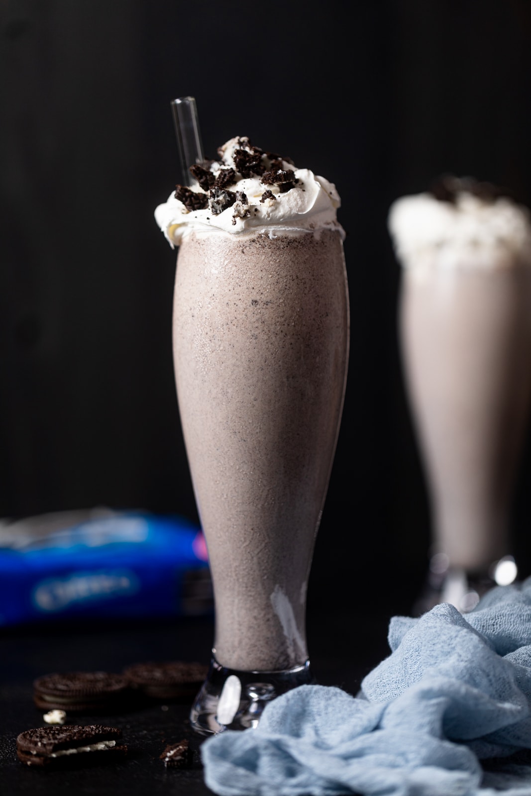 Tall glass filled with an Oreo Milkshake with a straw