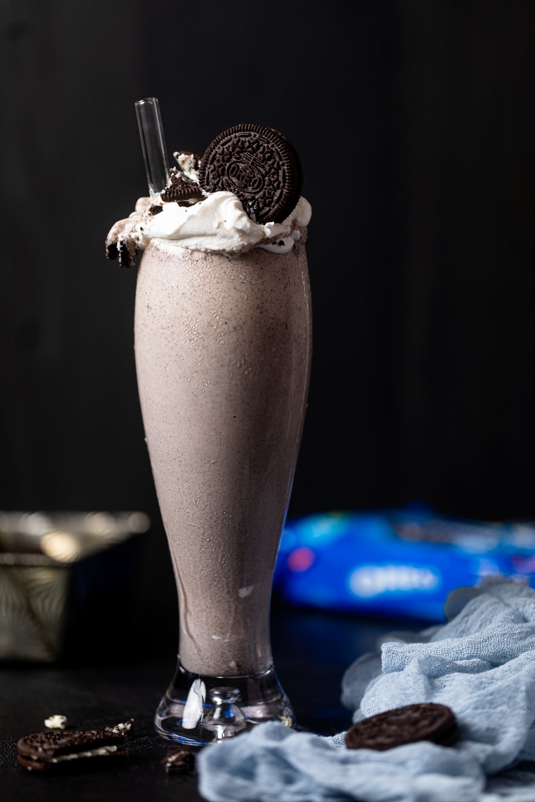 Tall glass filled with an Oreo Milkshake with a straw