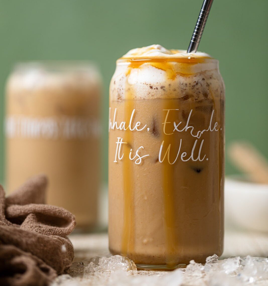Peanut Butter Caramel Iced Latte in a glass with script that reads "Inhale. Exhale. It is Well."