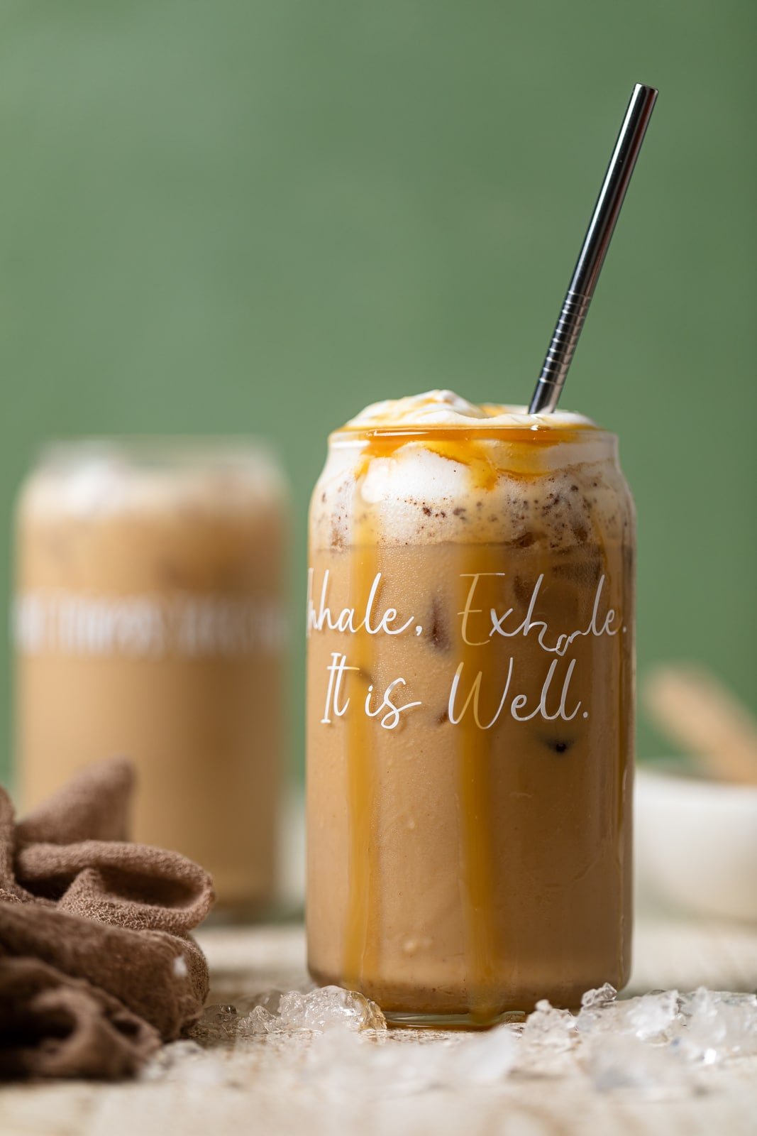 Peanut Butter Caramel Iced Latte in a glass with script that reads \"Inhale. Exhale. It is Well.\"