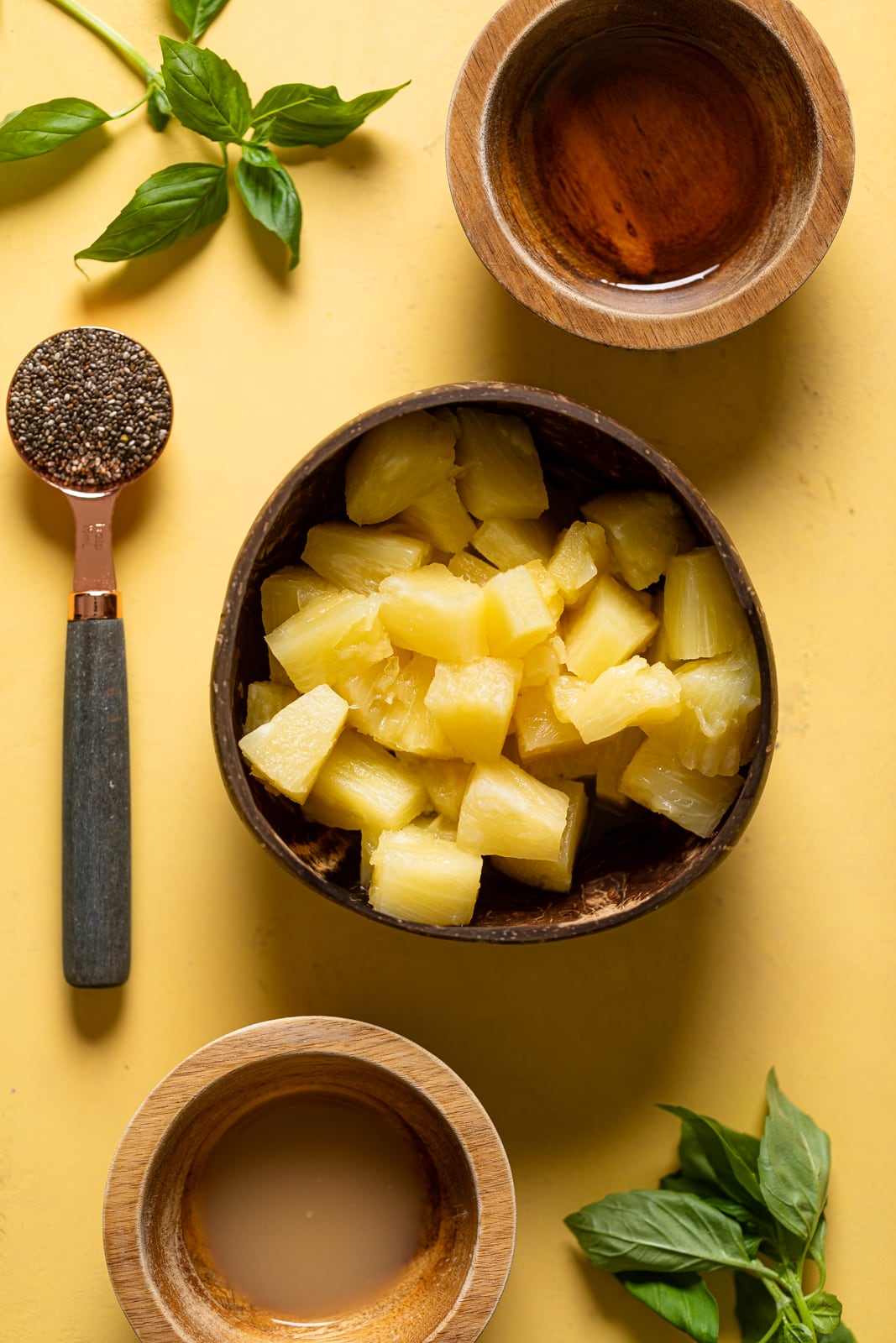 Ingredients for Pineapple Chia Seed Tropical Mocktail including pineapple chunks, chia seeds, and basil leaves