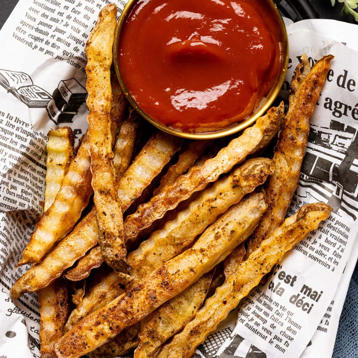 Up close shot of fries in food basket with a side of ketchup.