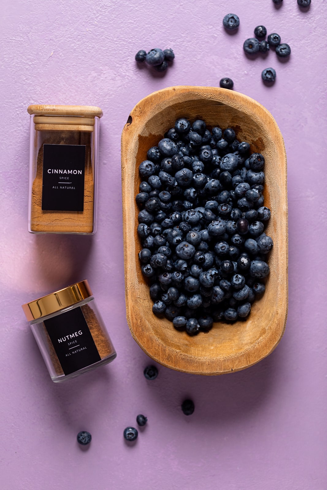 Bowl of blueberries next to jars of nutmeg and cinnamon