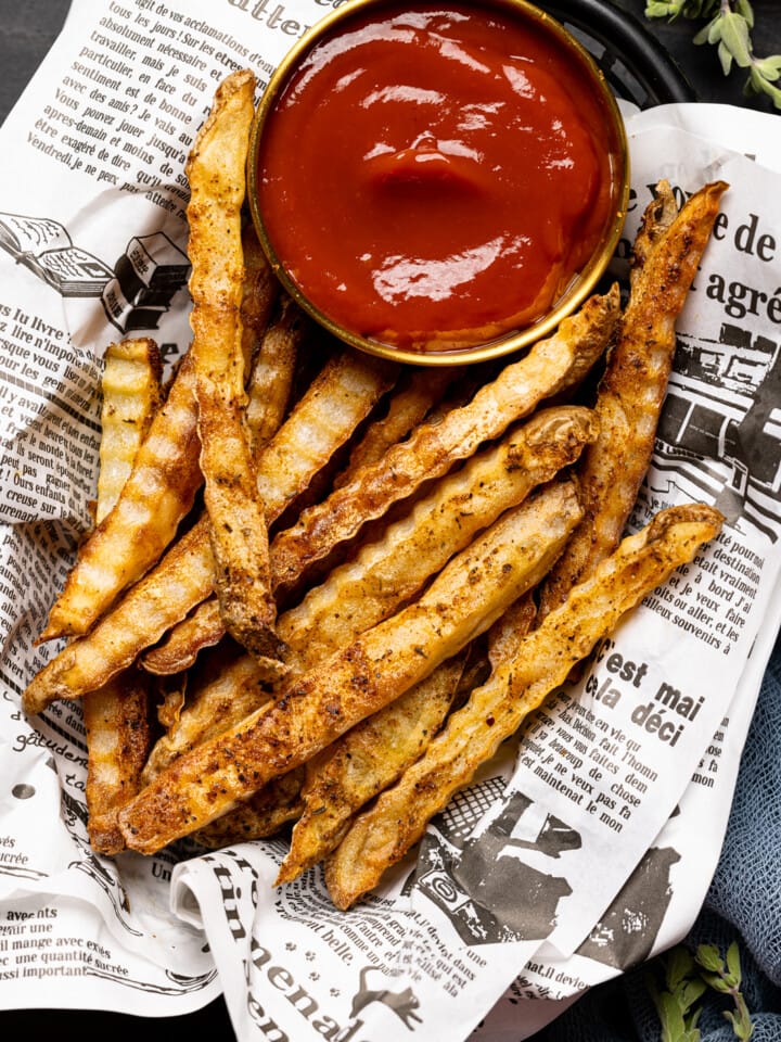 Up close shot of fries in food basket with a side of ketchup.