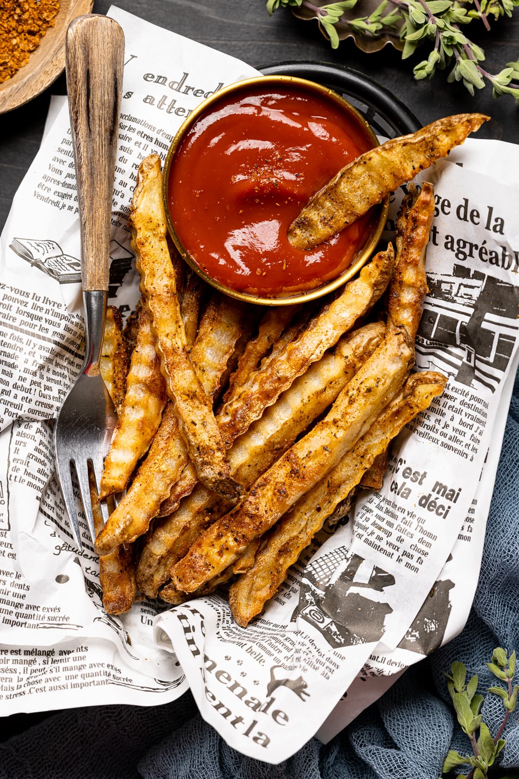 Fries in a food basket with ketchup and a fork.