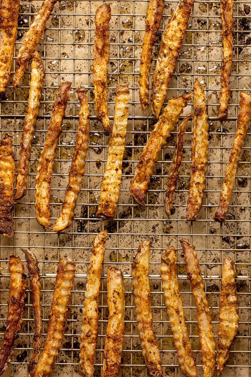 Baked crispy fries on a baking sheet lined with parchment paper.