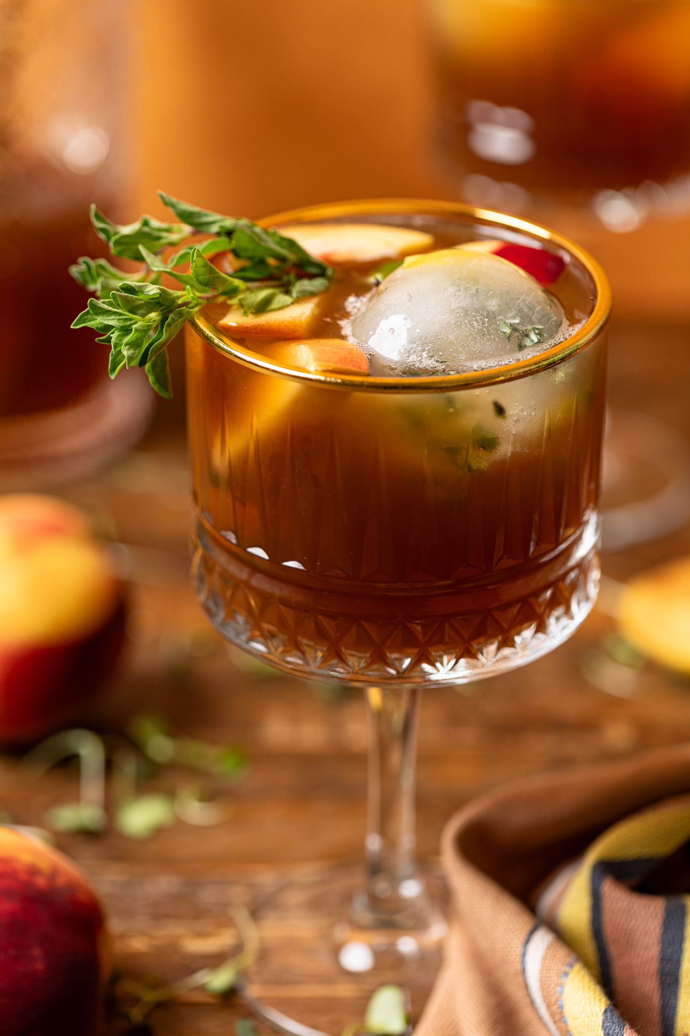 An image of peach iced tea in a tall glass with ice and peaches.