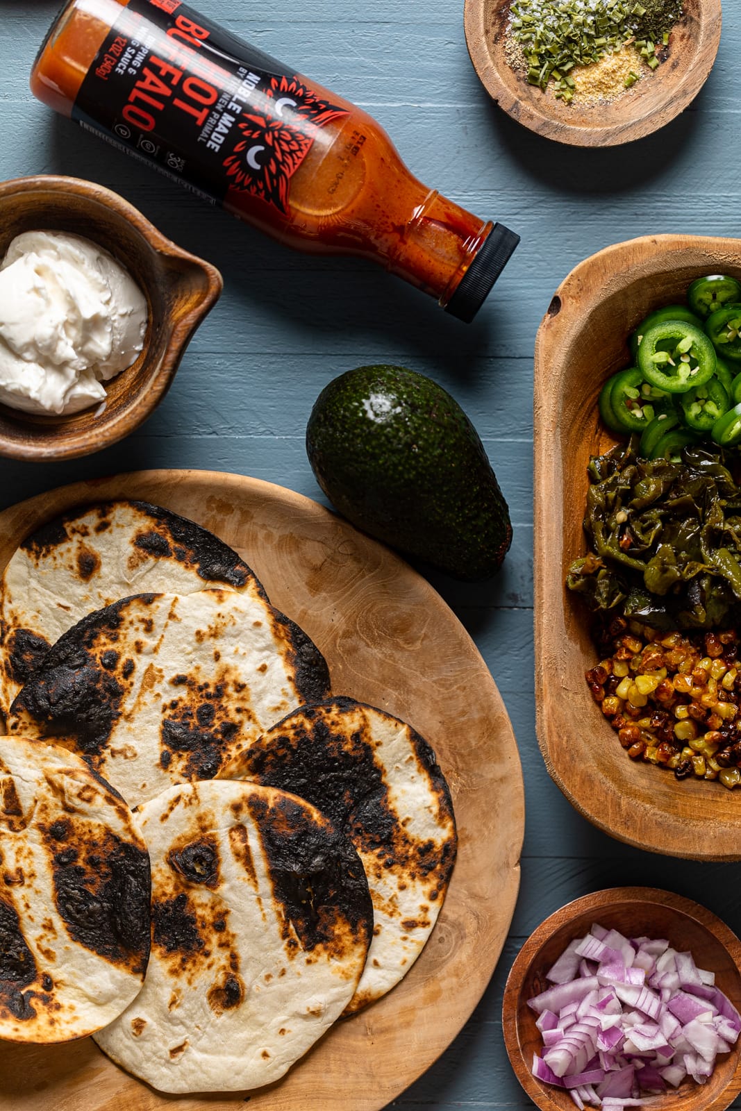 Ingredients for Summer Vegan Tacos including avocado, hot buffalo sauce, and red onion