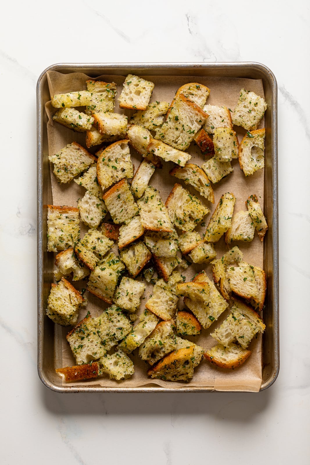 Seasoned, chopped bread on a baking sheet