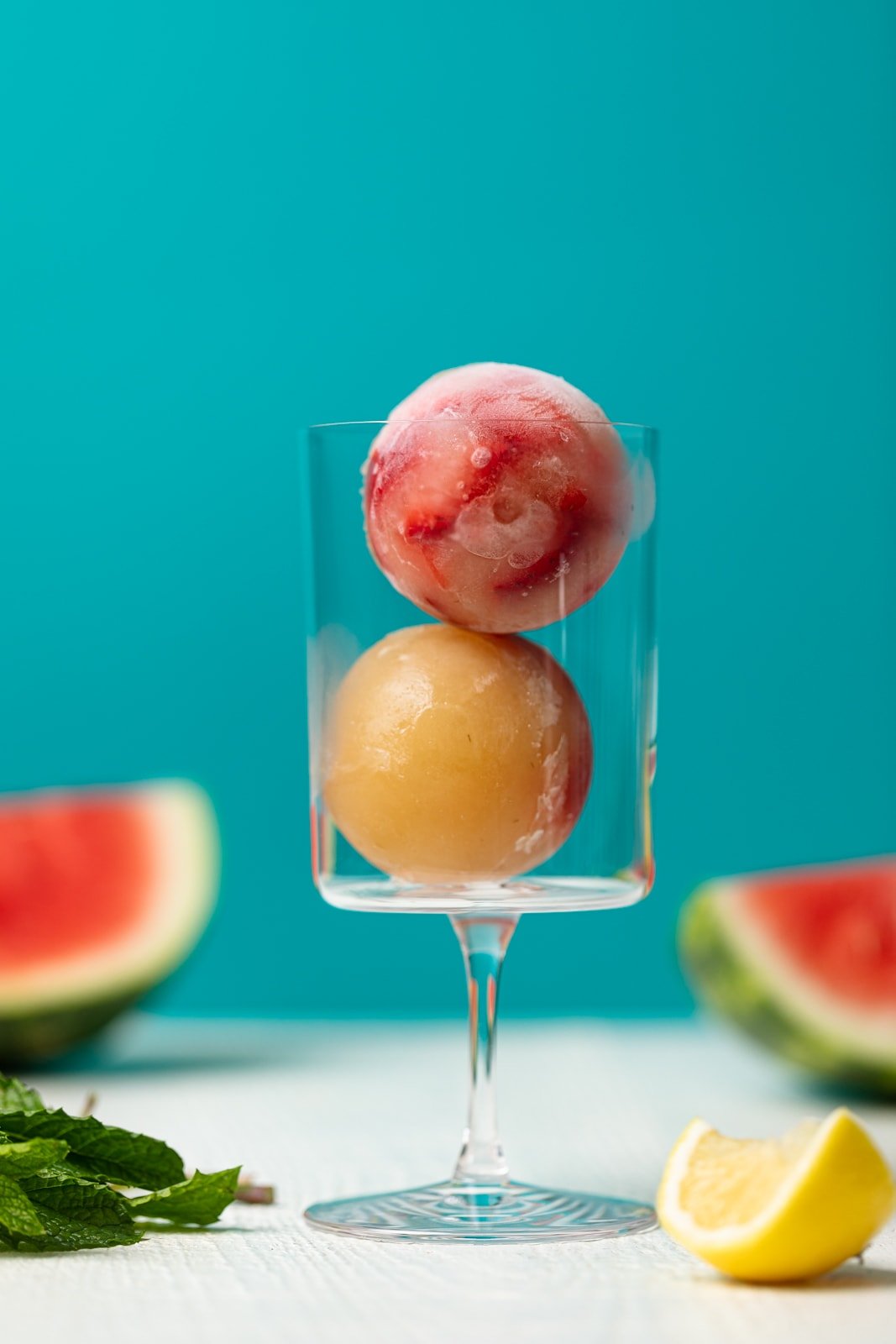 Two strawberry pineapple ice balls in a glass
