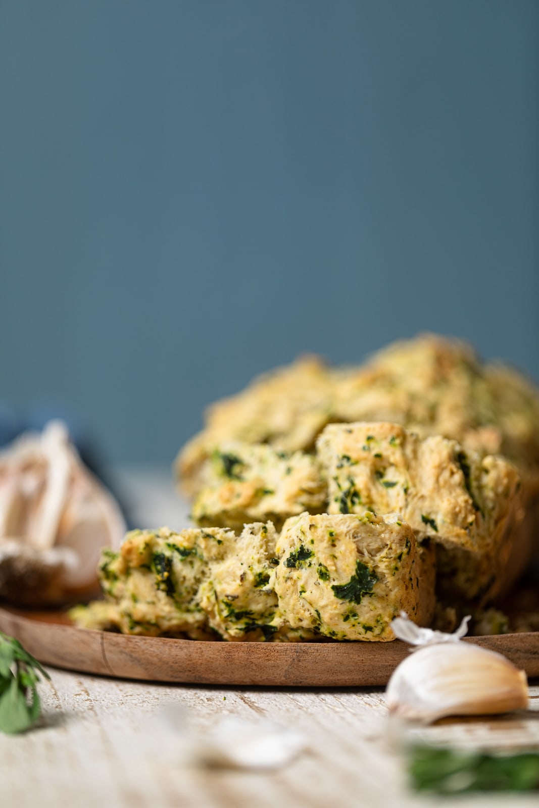 Slices of Vegan Garlic Herb Kale Bread on a wooden plate