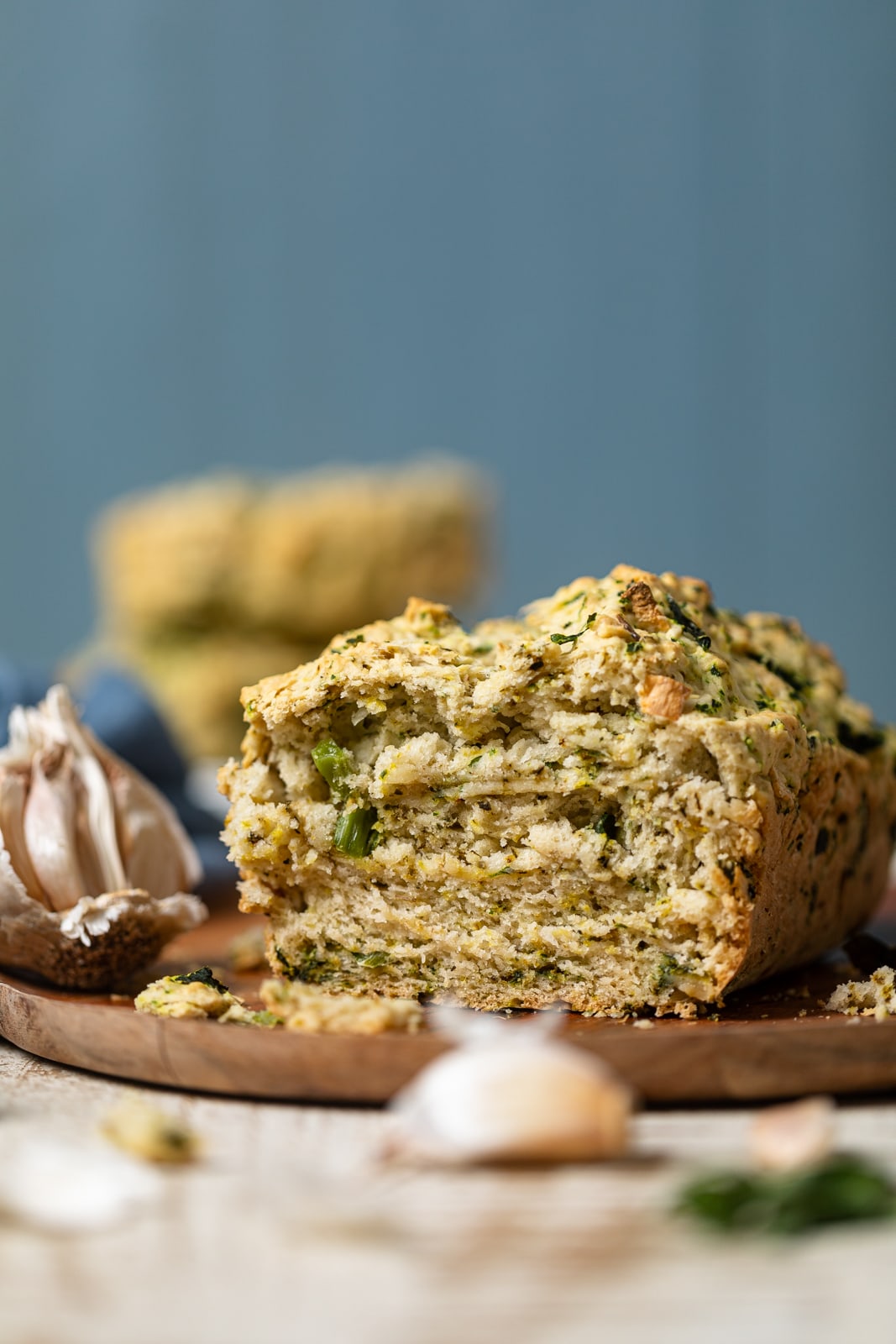 Vegan Garlic Herb Kale Bread on a wooden plate with garlic