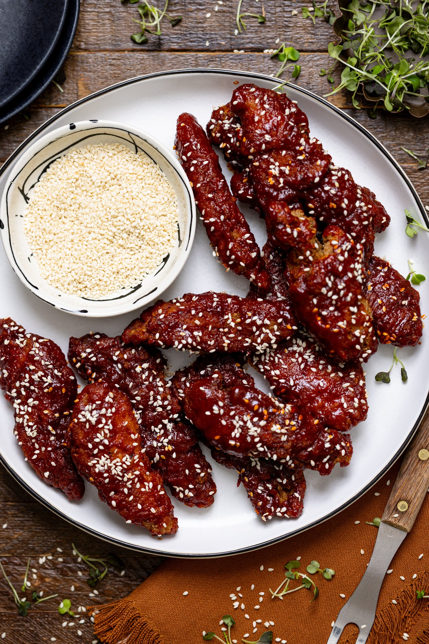 Delicious Gochujang Chicken Tenders on a platter with a side of black plates.