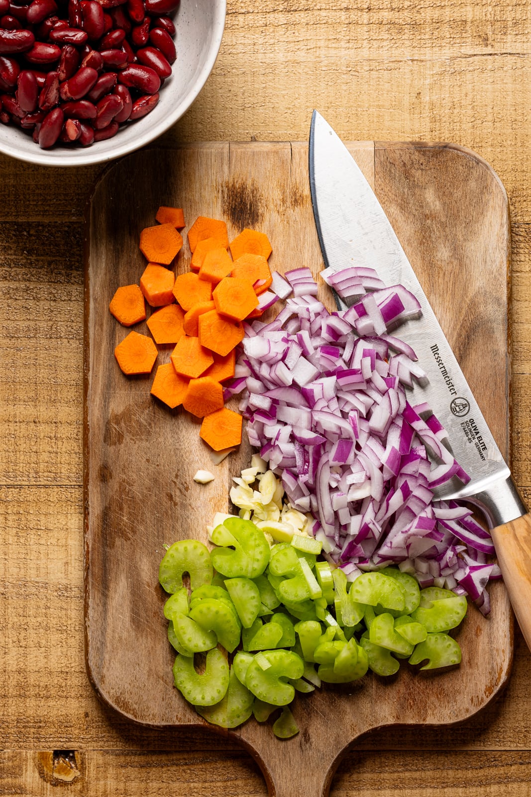 Chopped veggies on a cutting board with a knife. 
