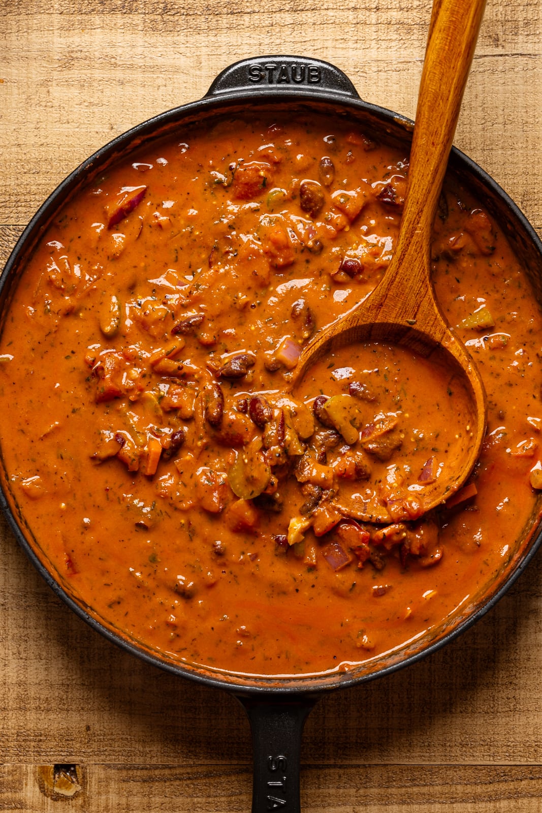 Bolognese sauce in a black skillet with a wooden spoon.