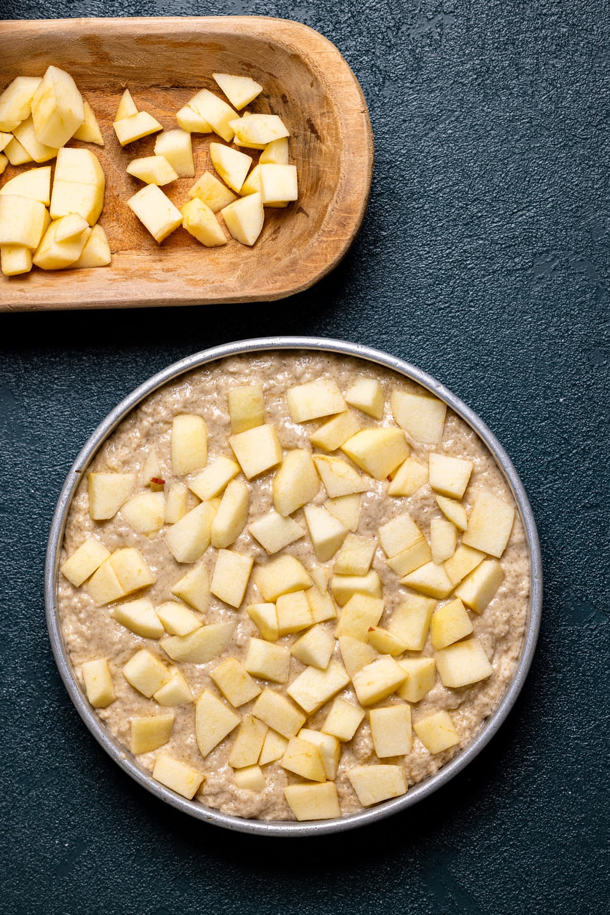 Circle pan of Apple Cinnamon Olive Oil Cake batter topped with apple pieces