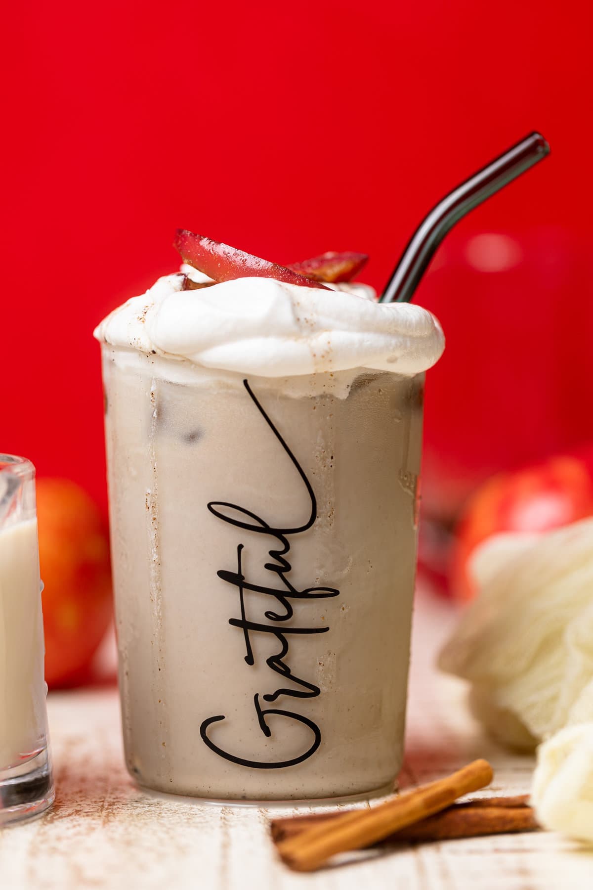 Apple Crisp Oatmilk Latte with a straw in a glass that has \"Grateful\" written on it