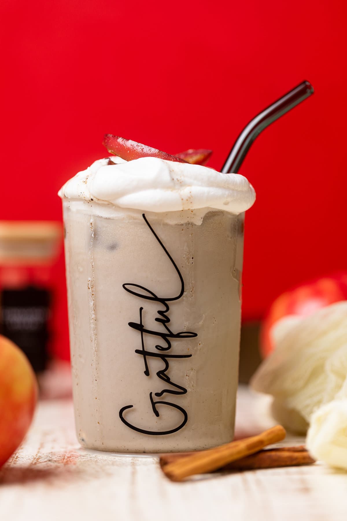Apple Crisp Oatmilk Latte with a straw in a glass that has "Grateful" written on it