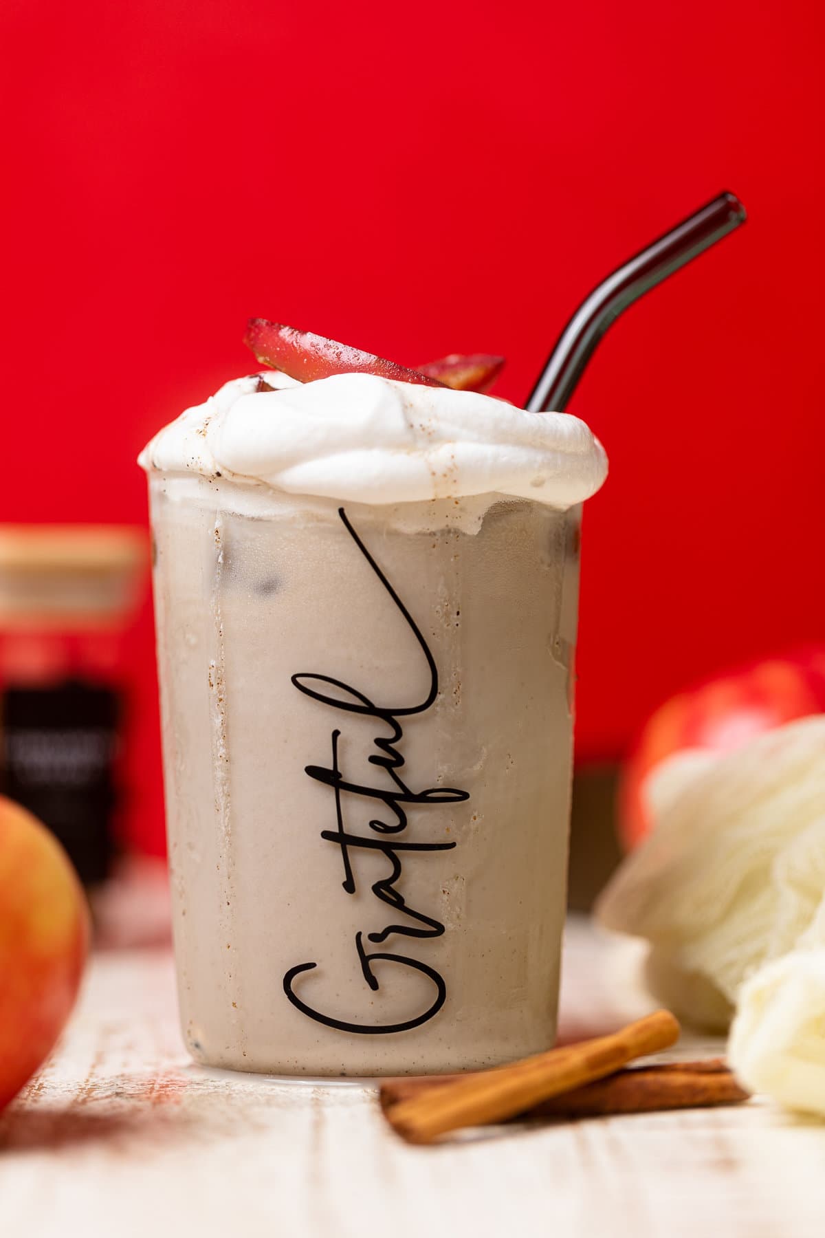 Apple Crisp Oatmilk Latte with a straw in a glass that has \"Grateful\" written on it